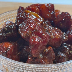 A glass bowl with bites of porkbelly in a bbq sauce