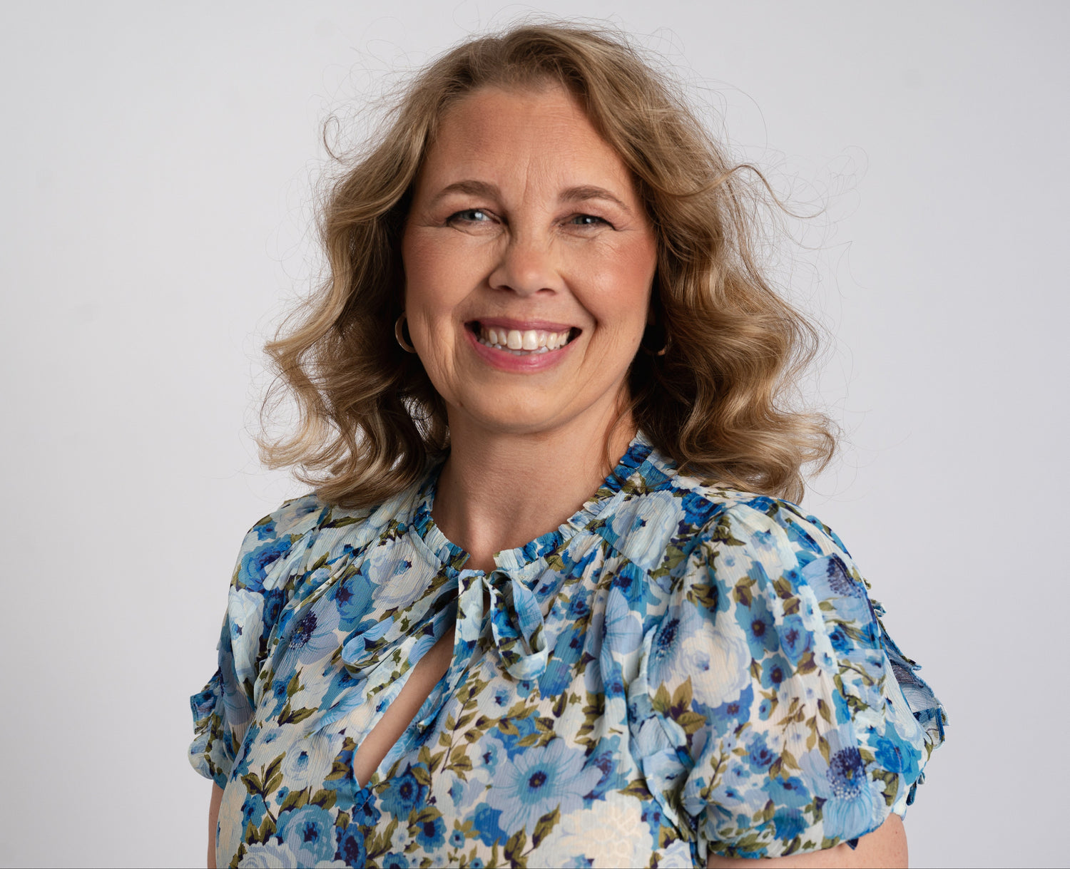 Woman wearing a floral blouse against a plain background