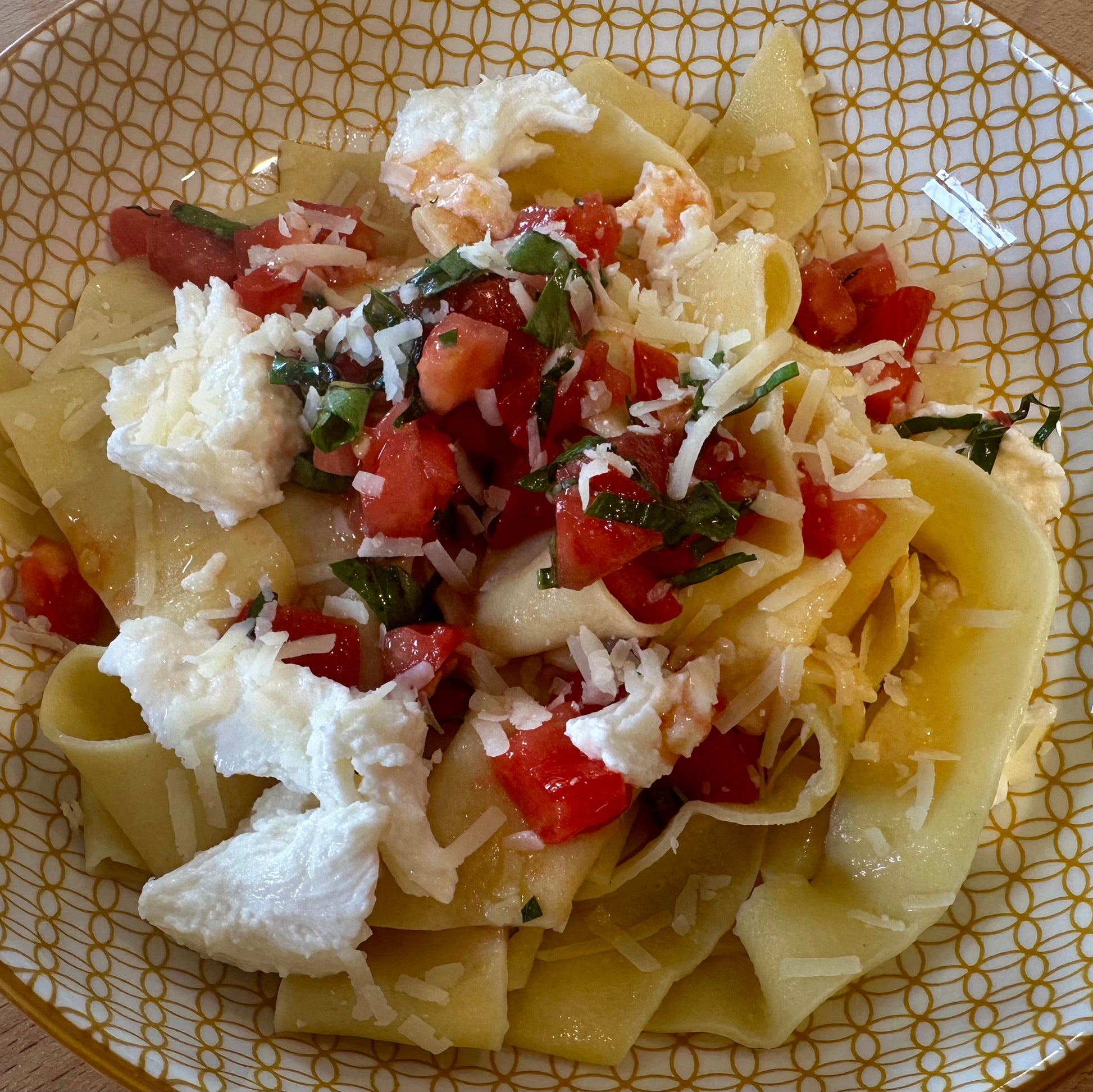 a yellow plate with fresh pasta, mozzarella and diced tomato sauce