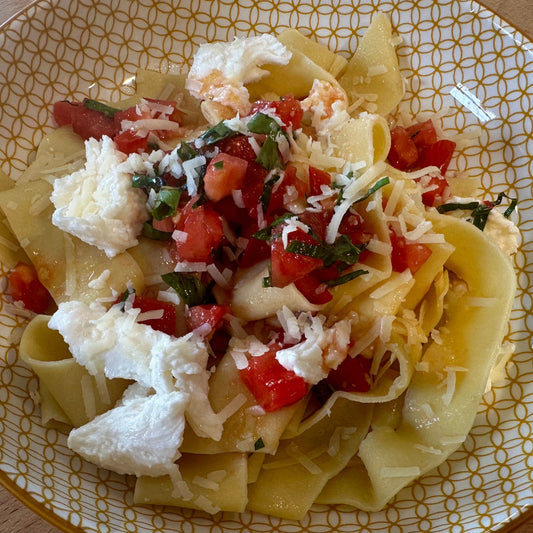 a yellow plate with fresh pasta, mozzarella and diced tomato sauce